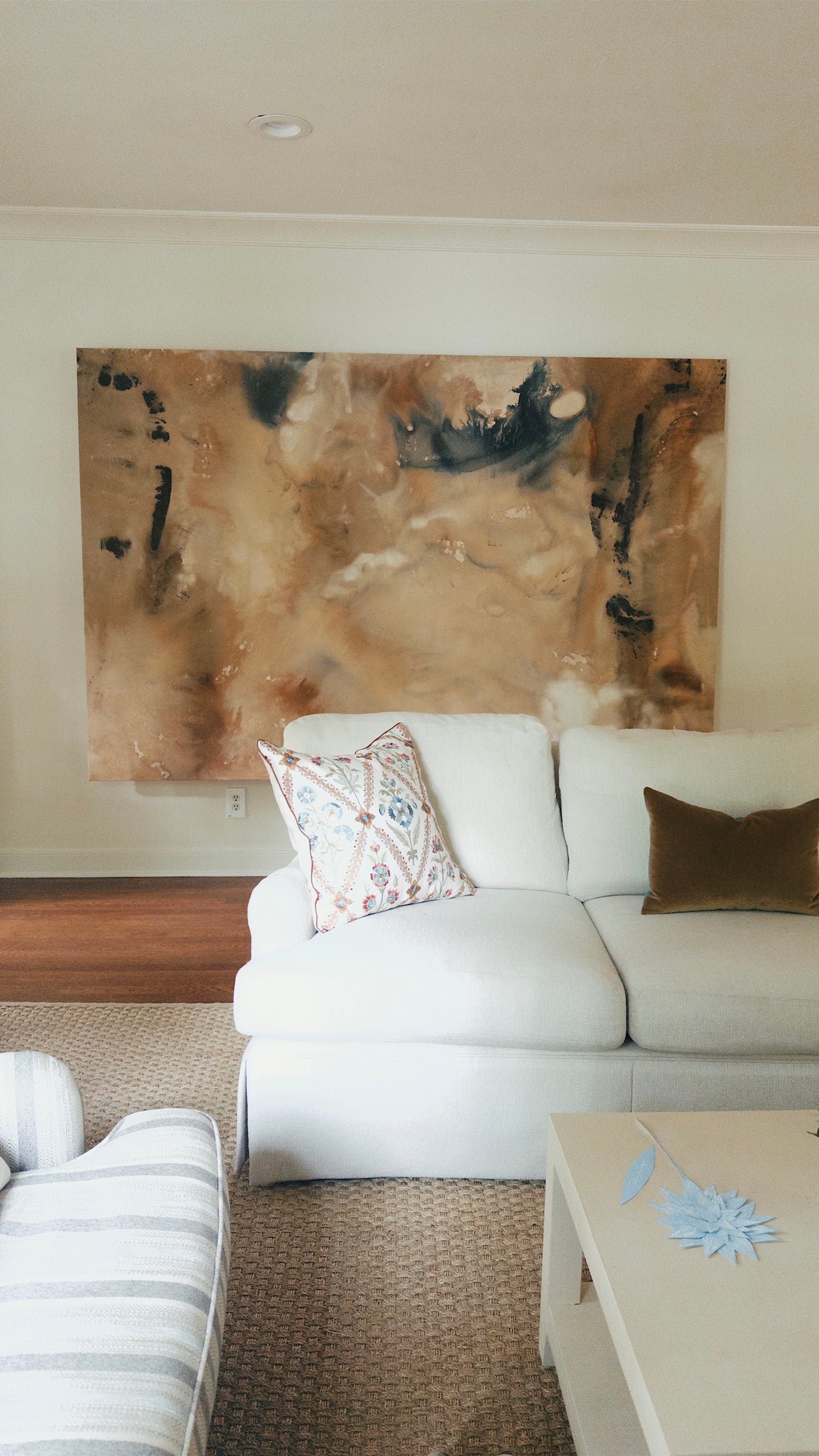 Living room with a white sofa, decorative pillows, and a large abstract painting on the wall.