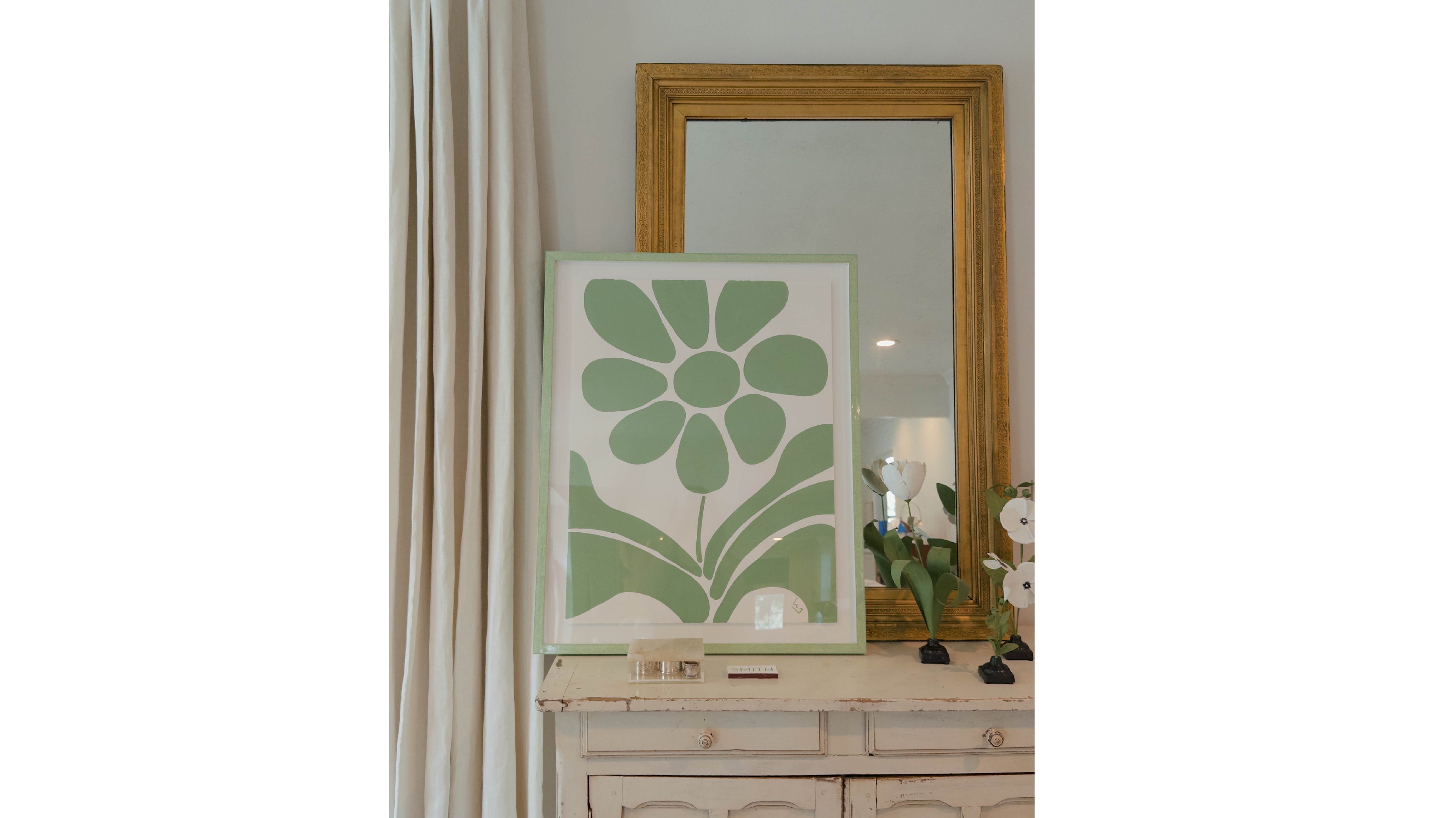 Decorative green flower print on a wall next to a mirror
